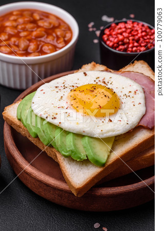 Delicious nutritious English breakfast with fried eggs, tomatoes and avocado 100779063