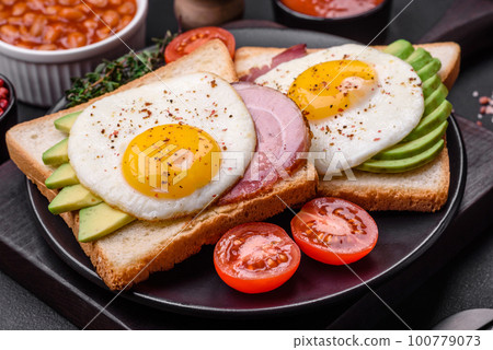 Delicious nutritious English breakfast with fried eggs, tomatoes and avocado 100779073