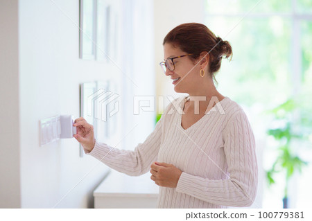Woman adjusting thermostat. Central heating. Woman adjusting thermostat. Central heating. 100779381