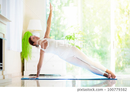 Yoga exercise at home. Fit woman stretching on mat Yoga exercise at home. Fit woman stretching on mat 100779382