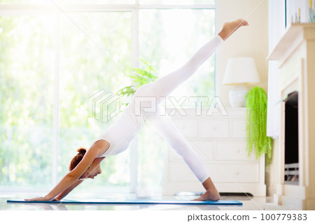 Yoga exercise at home. Fit woman stretching on mat Yoga exercise at home. Fit woman stretching on mat 100779383