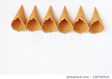 Several waffle cones lined in tower, smile, or even row, top vie 100780424