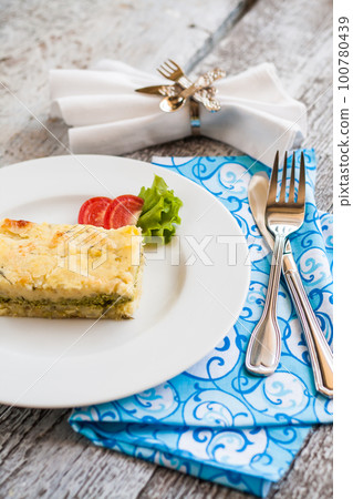 potato casserole with spinach on a plate and cutlery potato casserole with spinach on a plate and cutlery 100780439