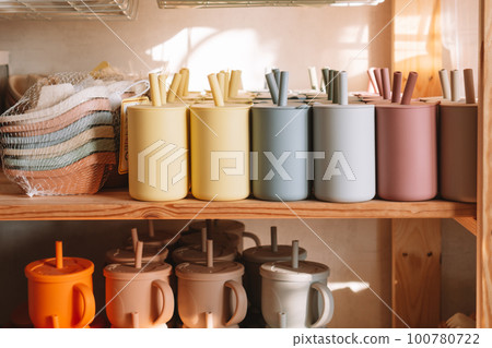 Multicolored silicone baby tableware stack with handles and forms on shelf of the store. Child healthcare, eco utensil 100780722