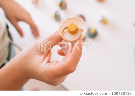 Cropped business woman hands, making and design craft silicone pacifiers for newborn babies. Small business, store. 100780725