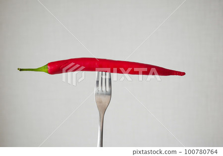 red chili pepper on the fork on white background . 100780764