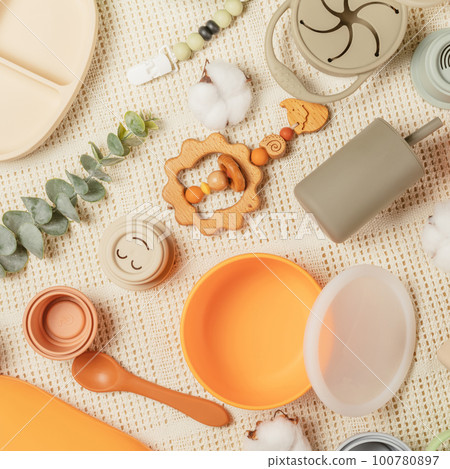 Pastel silicone kit of tableware, cutlery, accessories and wooden toys for children on white cotton cloth background. Pastel silicone kit of tableware, cutlery, accessories and wooden toys for children on white cotton cloth background. 100780897