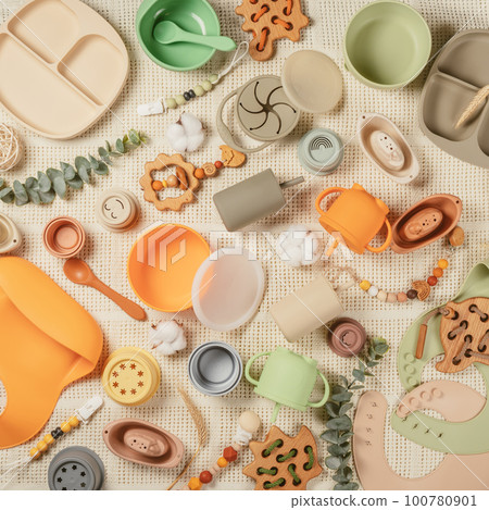 Pastel silicone collection of tableware, cutlery, bibs, accessories, wooden toys for children on white cloth background. Pastel silicone collection of tableware, cutlery, bibs, accessories, wooden toys for children on white cloth background. 100780901