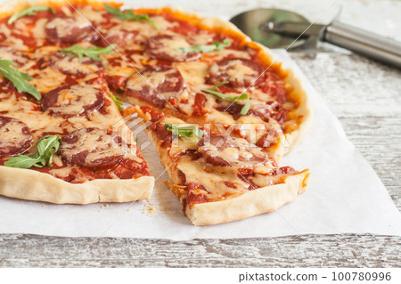 homemade pizza with salami, tomatoes and herbs 100780996