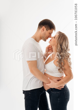 a couple waiting for a child in white T-shirts and jeans on a white background. a couple waiting for a child in white T-shirts and jeans on a white background. 100781058