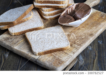 Chocolate butter spread on bread while cooking breakfast Chocolate butter spread on bread while cooking breakfast 100782527
