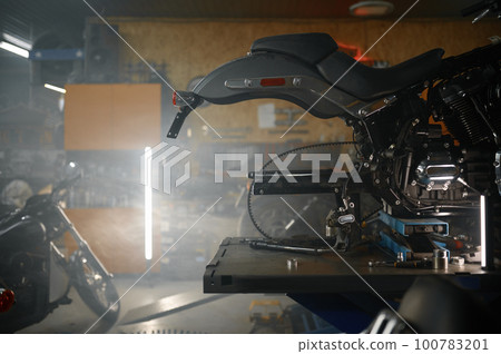 Disassembled motorcycle on table in biker garage workshop 100783201