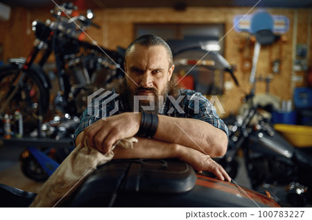 Portrait of mature biker man over his motorbike metal horse Portrait of mature biker man over his motorbike metal horse 100783227