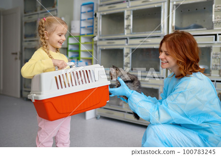 Happy mother and child taking kitten to home putting in carrier 100783245