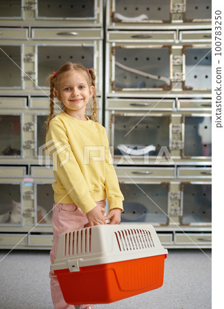 Portrait of little girl holding cage with new pet bought at veterinary shop 100783250