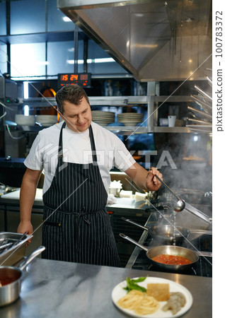 Chef adding white wine to frying pan with tomato sauce for pasta Chef adding white wine to frying pan with tomato sauce for pasta 100783372
