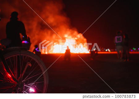 People walking towards sunset at a festival in the desert. Beautiful music festival in a desert.at night.Burning huge installations in the middle of a desert. 100783873