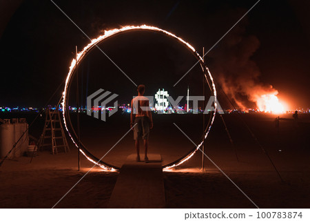 People walking towards sunset at a festival in the desert. Beautiful music festival in a desert.at night at the Burning Man Festival. 100783874