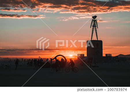 People walking towards sunset at a festival in the desert. Beautiful music festival in a desert at the Burning Man Festival. People walking towards sunset at a festival in the desert. Beautiful music festival in a desert at the Burning Man Festival. 100783974