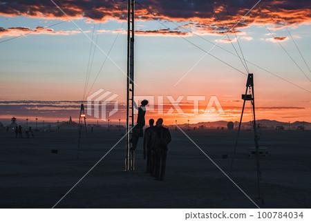 People walking towards sunset at a festival in the desert. Beautiful music festival in a desert at the Burning Man Festival. People walking towards sunset at a festival in the desert. Beautiful music festival in a desert at the Burning Man Festival. 100784034