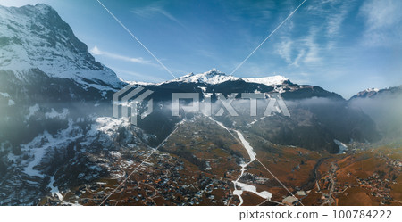 Aerial panorama of the Grindelwald, Switzerland village view near Swiss Alps mountains panorama landscape, wooden chalets on green fields and high peaks in background, Bernese Oberland, Europe. 100784222