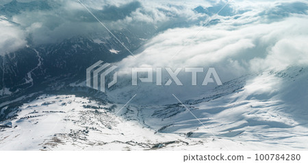 Alpine landscape with peaks covered by snow and clouds. Magical clouds covering peaks of the mountains at the famous St. Anton am Arlberg ski resort. Alpine landscape with peaks covered by snow and clouds. Magical clouds covering peaks of the mountains at the famous St. Anton am Arlberg ski resort. 100784280