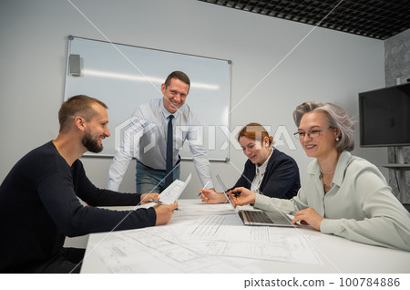 Caucasian man leading a presentation to colleagues at a white board.  100784886
