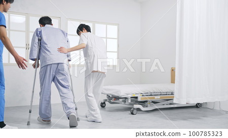 Patient and care staff rehabilitating with crutches 100785323