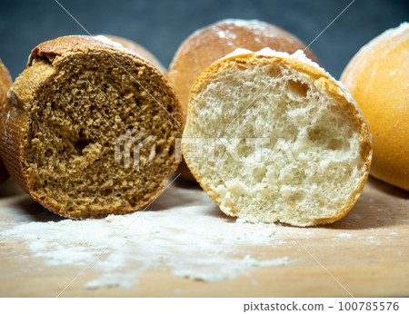 Bakery products. Table in the bakery. Buns on a cutting board. Rye and wheat buns. Bakery products. Table in the bakery. Buns on a cutting board. Rye and wheat buns. 100785576