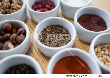set of spices on wooden background, caraway cumin, hazelnut, pine nut 100786350