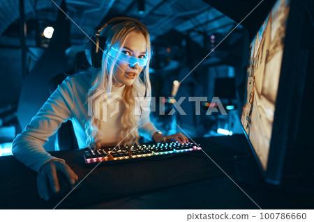 A blonde is playing PC games. Cyberpunk neon style. 100786660