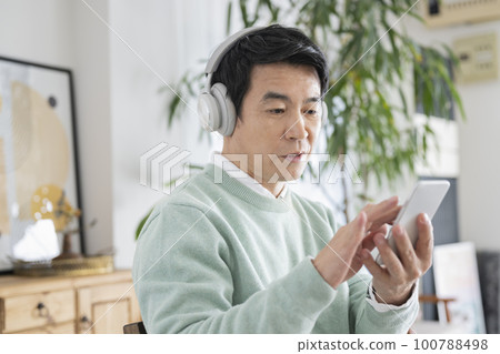 Men in their 50s listening to music at home on holidays Men in their 50s listening to music at home on holidays 100788498