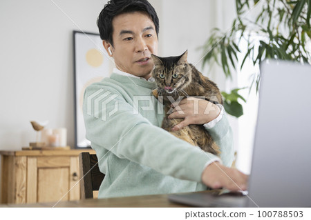 一個 50 多歲的男人在一個有貓的房間裡做文案工作 100788503