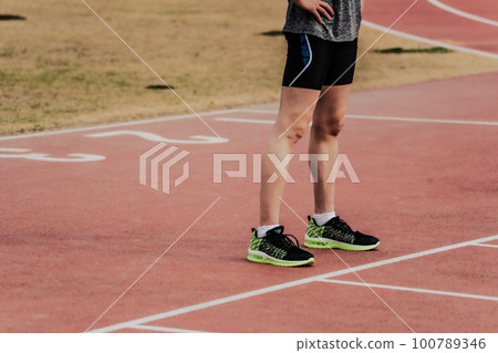 Runners standing on starting line on athletics track 100789346