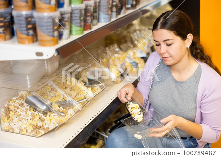 Young woman buying dry dog food at pet store 100789487