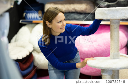Woman choosing cat scratching post for cats in pet shop Woman choosing cat scratching post for cats in pet shop 100789546