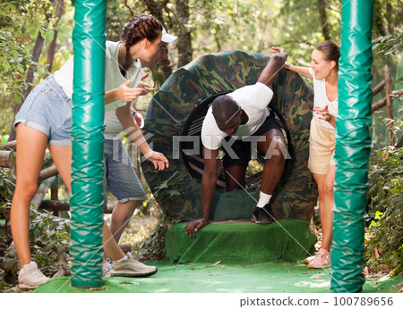 Friends help each other overcome an obstacle course Friends help each other overcome an obstacle course 100789656