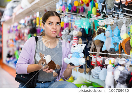 Young woman looking for safe toy for pet in shop 100789680