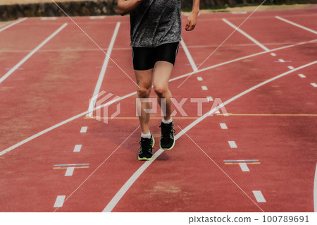 Male runner making a start dash on the track of the athletics stadium 100789691