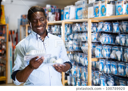 African american man choices energy saving lamp at hardware store African american man choices energy saving lamp at hardware store 100789920