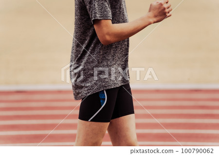 Male runner warming up while waving his arms on an athletic track 100790062