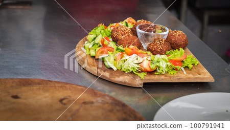 Falafel plate with vegetables salad and sauce on the kitchen table close up. 100791941