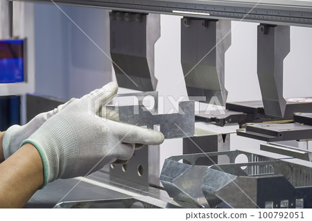 Close up the bending machine operator hold the sheet metal parts and  wear the rubber glove. 100792051