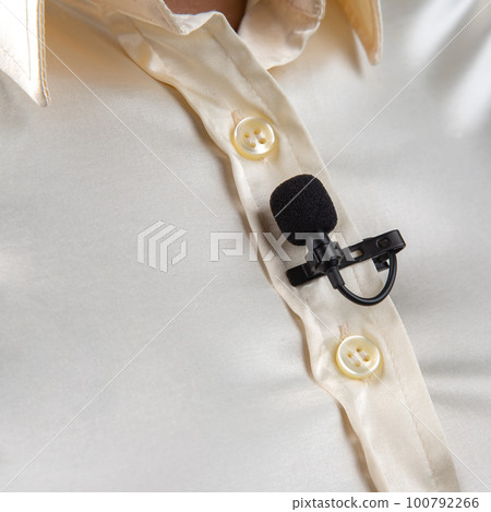 The lavalier microphone is secured with a clip on a women shirt close-up 100792266