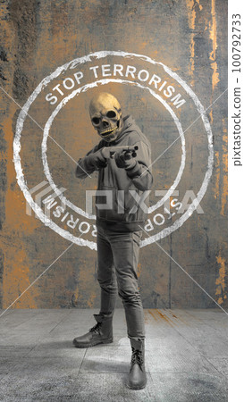 A man wearing a mask holding a gun with stop terrorism sign A man wearing a mask holding a gun with stop terrorism sign 100792733
