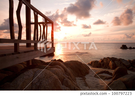 Beautiful sunset view of tropical idyllic summer landscape with colorful sky on and wooden pier.  100797223