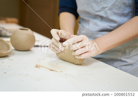 Closeup hands of ceramic artist wedging clay on a desk in art studio Closeup hands of ceramic artist wedging clay on a desk in art studio 100801552