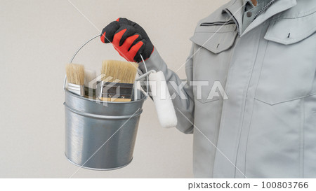A man in work clothes with a bucket containing painting tools 100803766