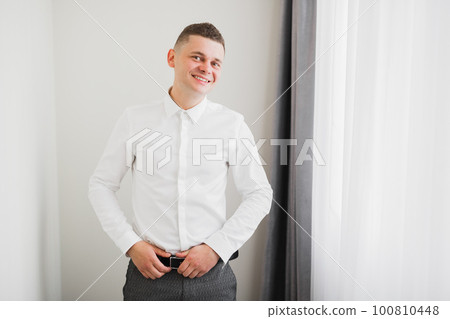 Grooms morning preparation. Handsome man getting dressed and preparing for the wedding Grooms morning preparation. Handsome man getting dressed and preparing for the wedding 100810448