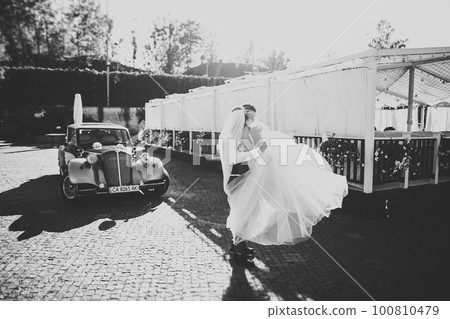 Wedding bride and groom, elegant couple staying near retro wedding car Wedding bride and groom, elegant couple staying near retro wedding car 100810479